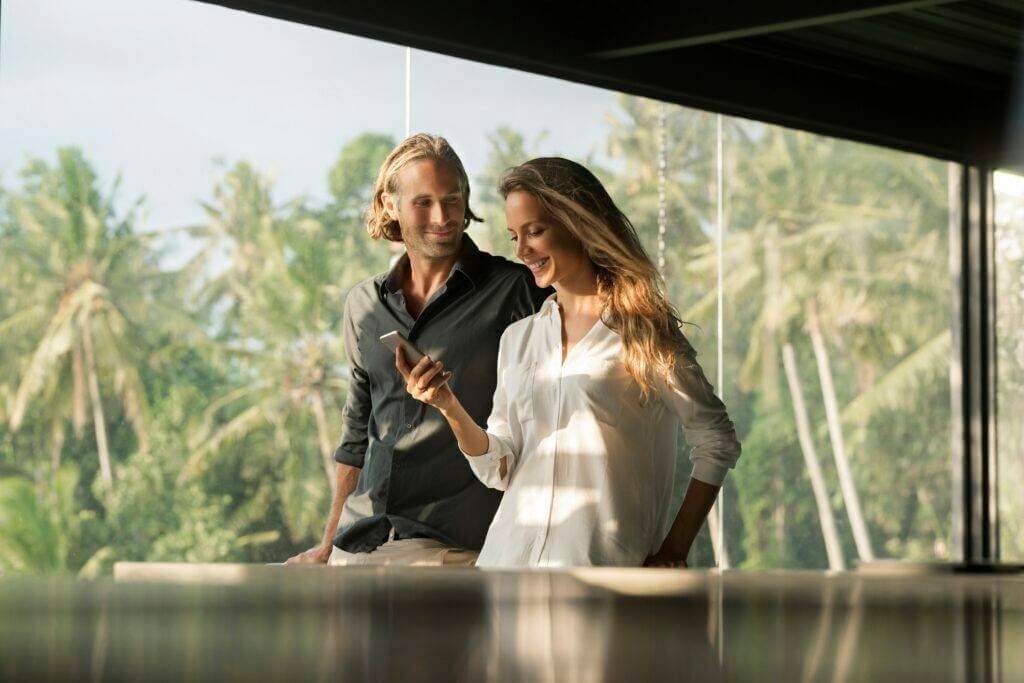 Smiling couple with smartphone in design house